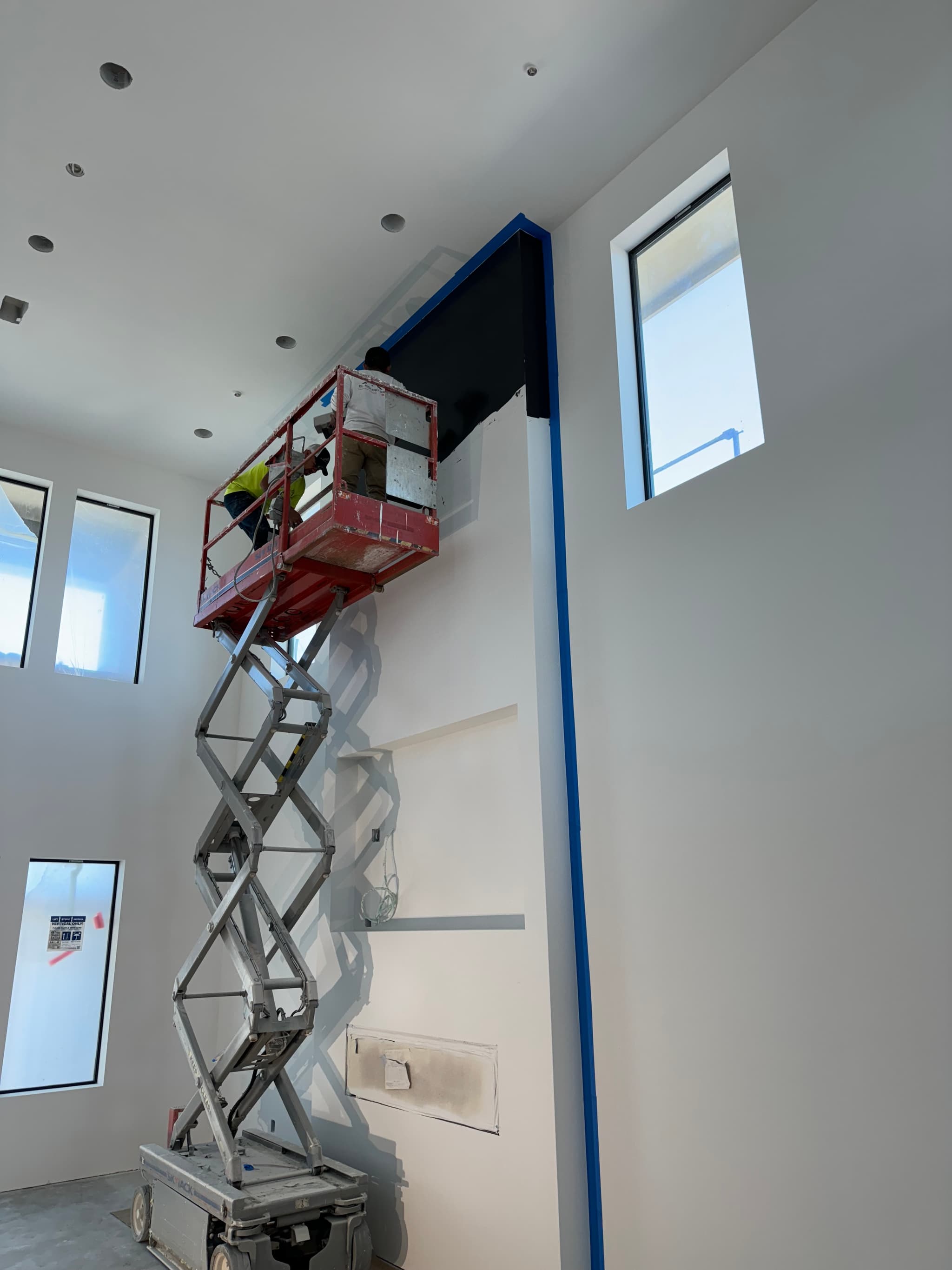 Builders reviewing plans inside a framed residential project